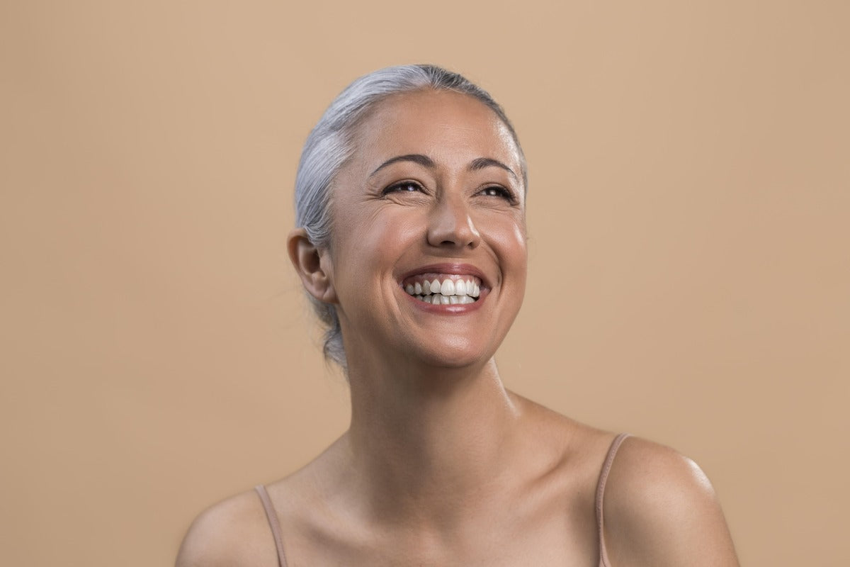 Smiling older woman with gray hair pulled back, her face radiant and glowing.