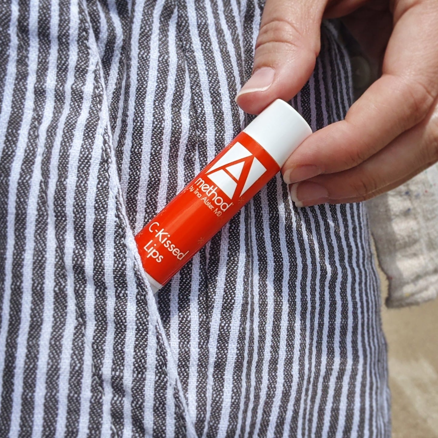 Lip balm tube in pocket of striped fabric.
