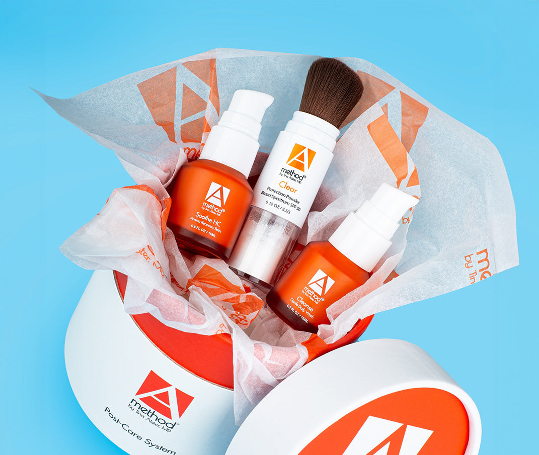 Post-care skincare system gift set in orange box, includes balm, powder, and cleanser.