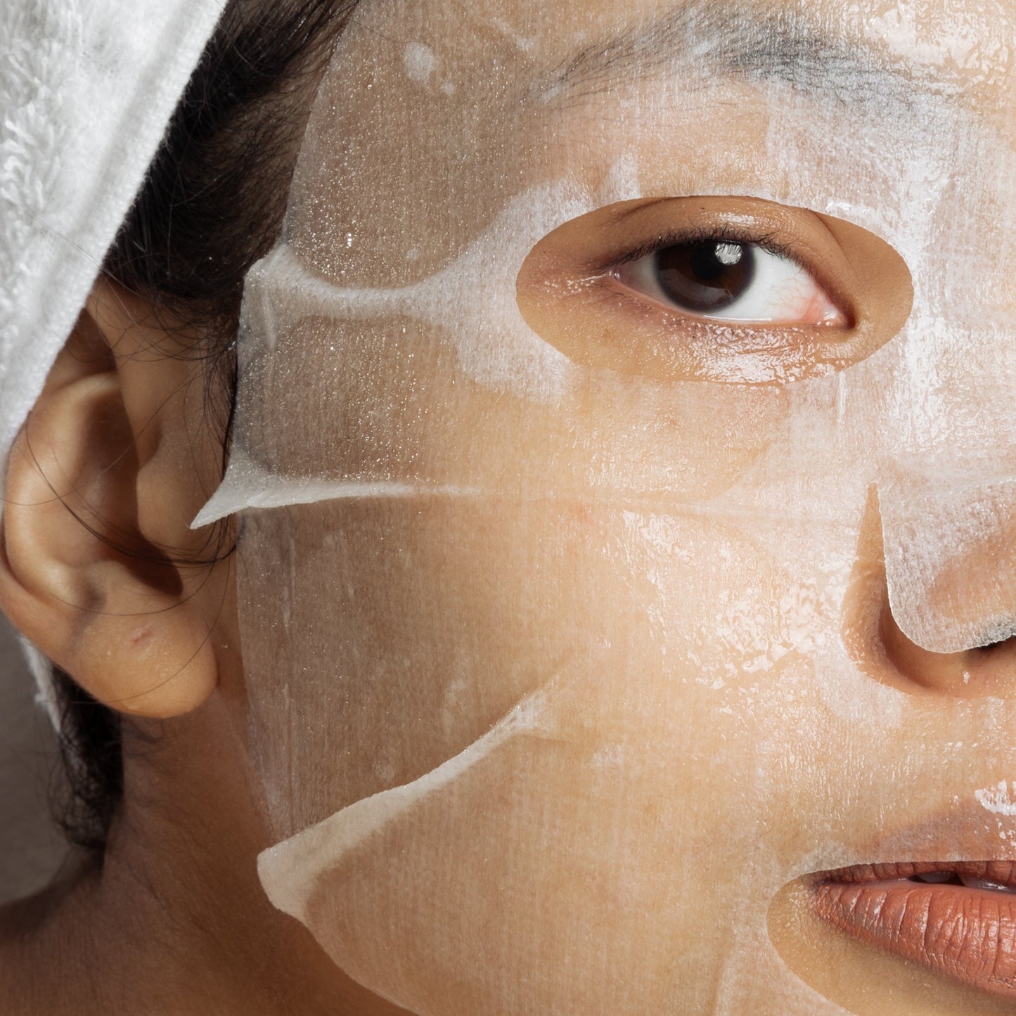 Close-up of a person using a hydrating facial sheet mask.