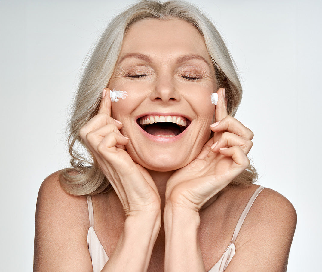 Happy woman applying face cream, radiant smile.