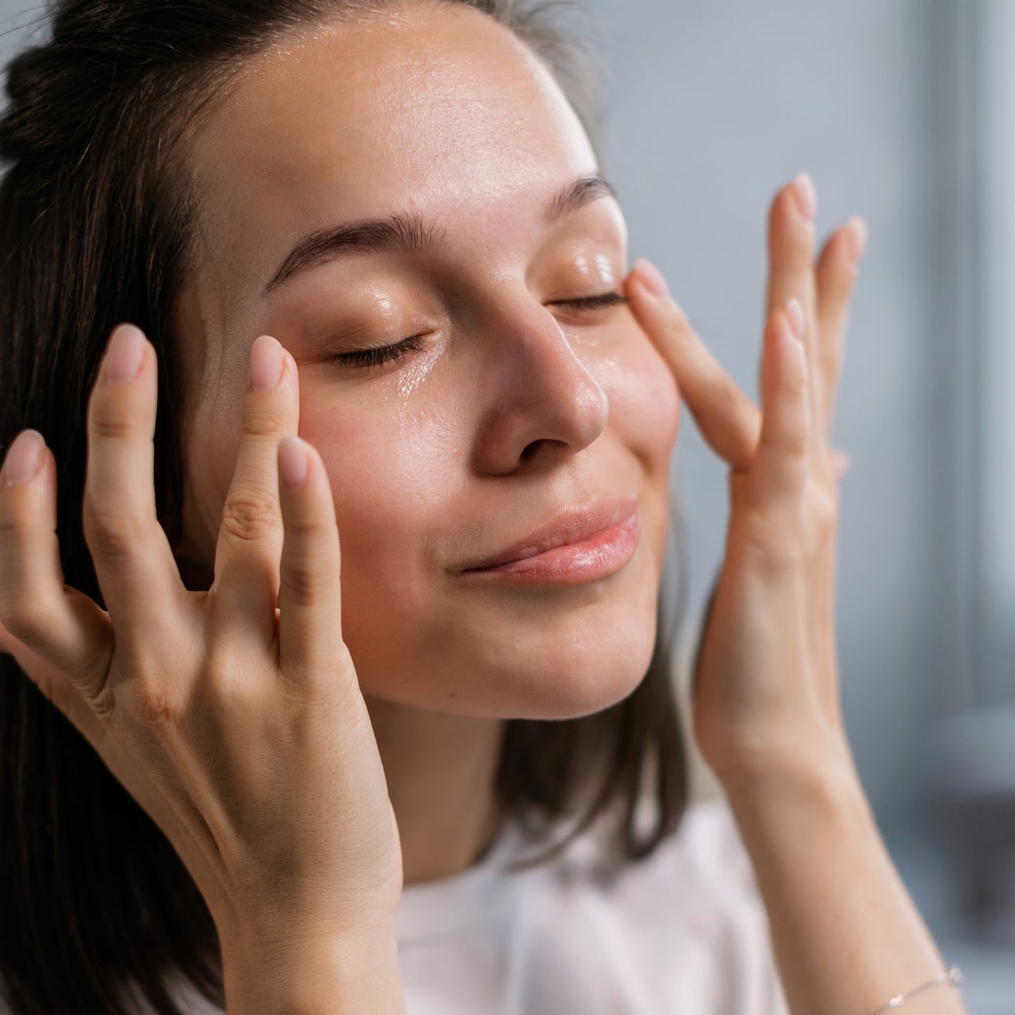 Woman gently applying eye cream, promoting brighter, smoother skin.