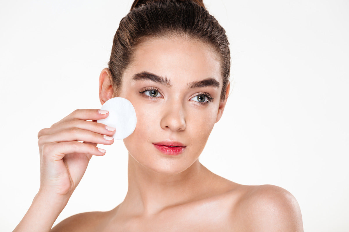 A woman uses blemish pads as part of her skincare routine, applying one to her face.