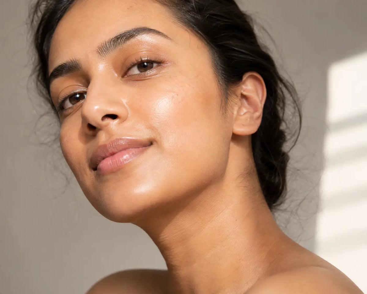Close-up of a woman with clear, smooth-looking skin in soft natural light showing a refined, pore-minimized complexion