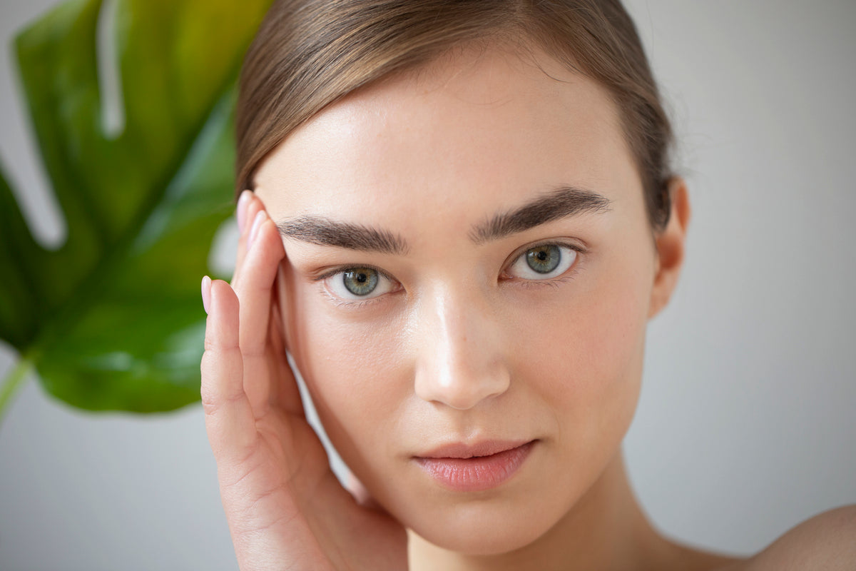 Close-up of a woman gently touching the side of her face, highlighting smooth skin and natural eye area.