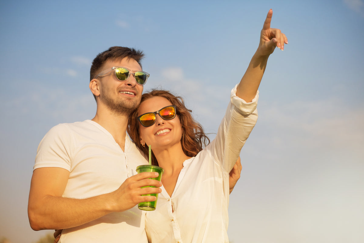Couple wearing sunglasses outdoors in sunny weather, enjoying time together with visible sun exposure, illustrating the need for powder sunscreen for convenient midday SPF touch-ups.