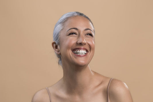 Smiling older woman with gray hair pulled back, her face radiant and glowing.