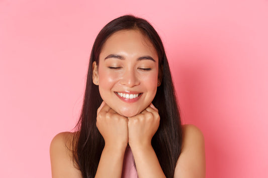 Smiling woman with smooth, glowing-looking skin against a pink background, representing results often associated with using a chemical peel kit.