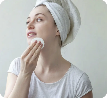 Woman applying a skincare pad to her face after cleansing as part of a niacinamide and retinol evening routine