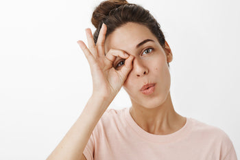 Person making a playful gesture around one eye while illustrating concerns addressed by the best eye cream for crow's feet and undereye care.