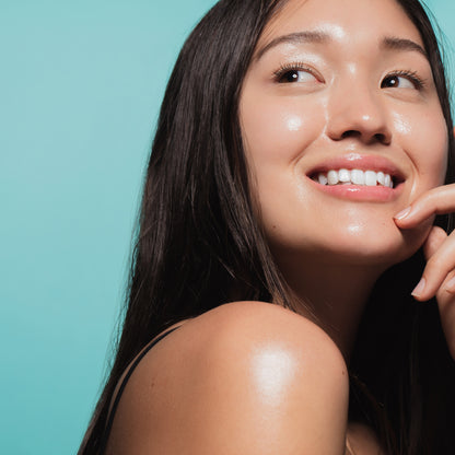 Woman with radiant, healthy-looking skin against a teal backdrop.
