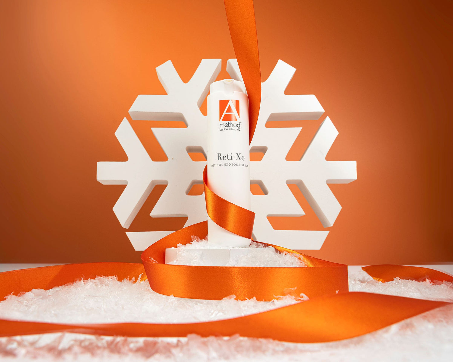 Reti-XO retinol serum wrapped in an orange ribbon with snowflake décor, featured as a holiday skincare gift.
