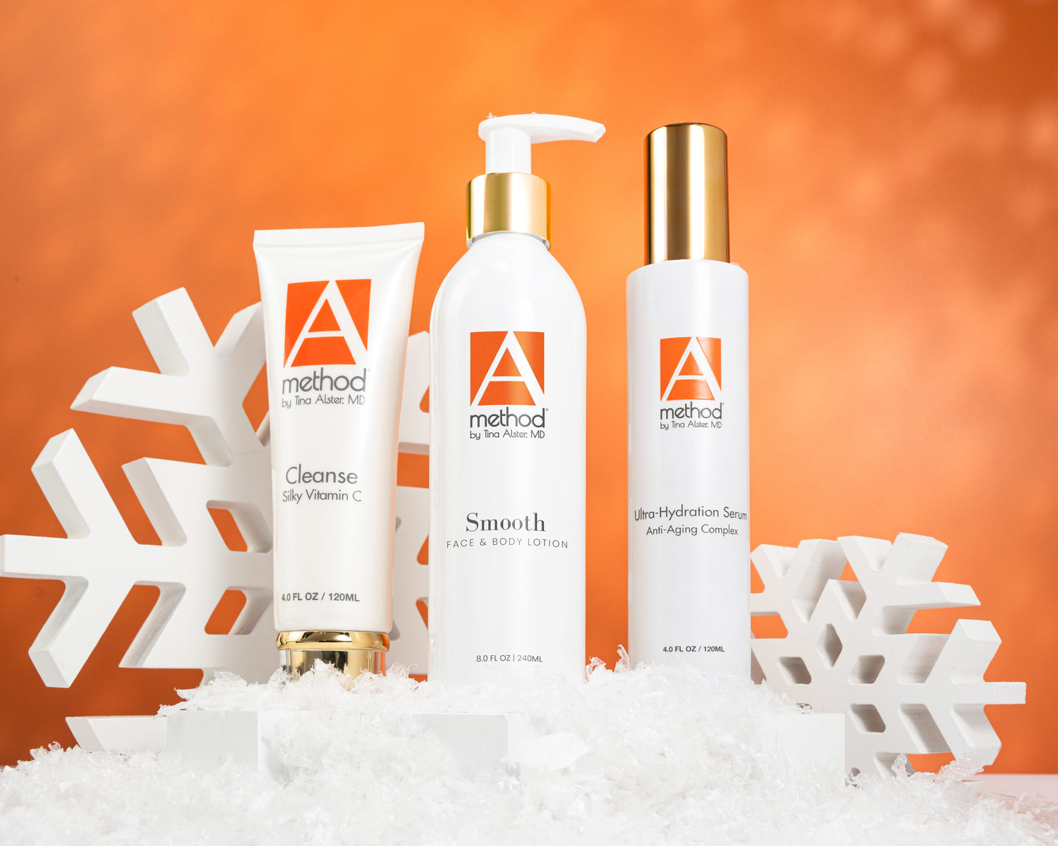 Silky Vitamin C Cleanser, Smooth Lotion, and Ultra-Hydration Serum displayed with snowflakes as a holiday skincare gift set.